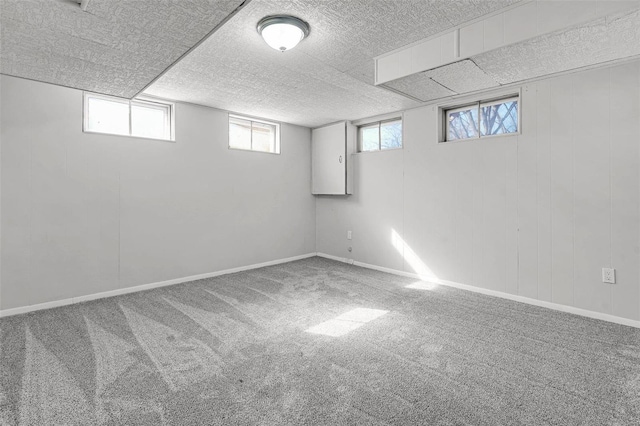 basement with carpet, a textured ceiling, and baseboards