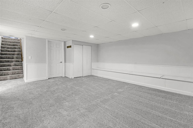 spare room with a wainscoted wall, recessed lighting, carpet flooring, a drop ceiling, and stairs