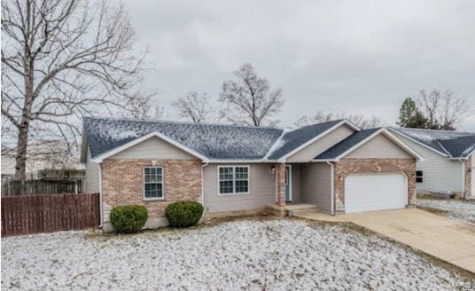 ranch-style home with a garage, concrete driveway, brick siding, and fence