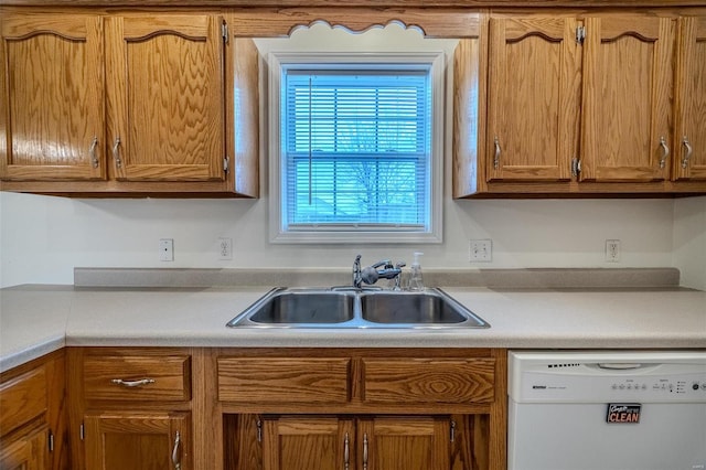 kitchen featuring dishwasher, light countertops, brown cabinetry, and a sink