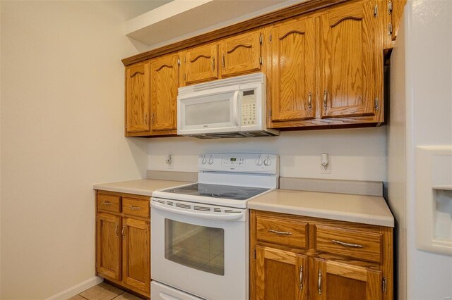 kitchen with white appliances, baseboards, brown cabinetry, and light countertops