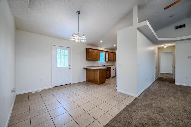 kitchen with brown cabinets, light countertops, visible vents, and dishwasher