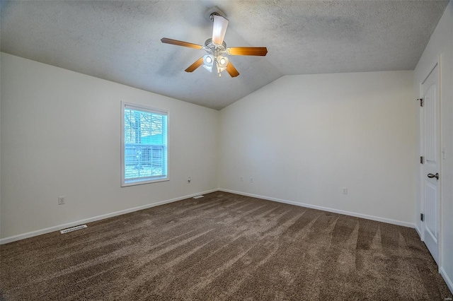 spare room with visible vents, vaulted ceiling, a textured ceiling, and dark colored carpet