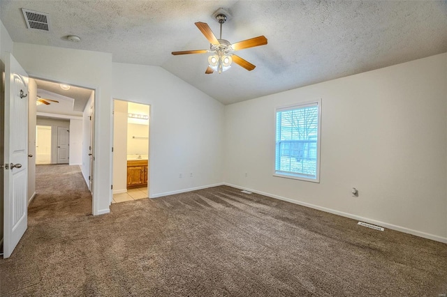 unfurnished bedroom with light carpet, visible vents, vaulted ceiling, and a textured ceiling