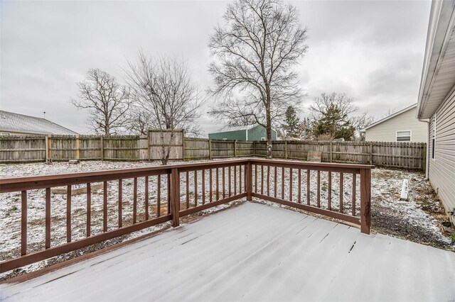 snow covered deck with a fenced backyard