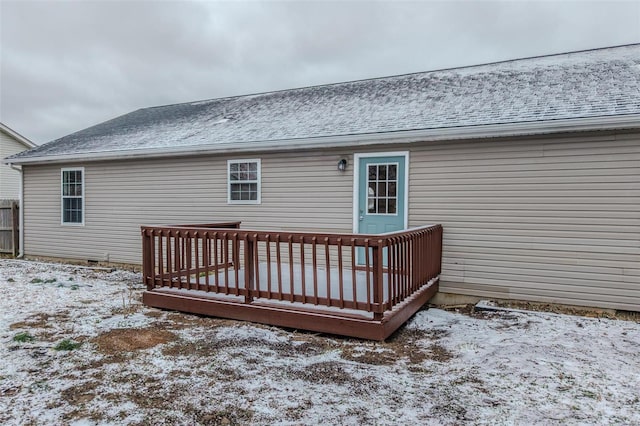 snow covered back of property with roof with shingles and a wooden deck