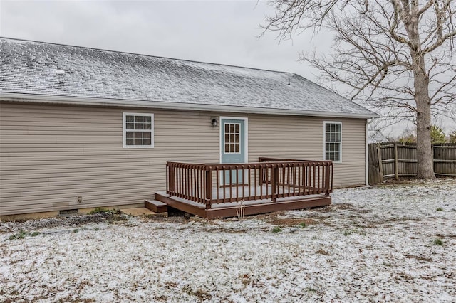 snow covered rear of property with a deck, a shingled roof, crawl space, and fence