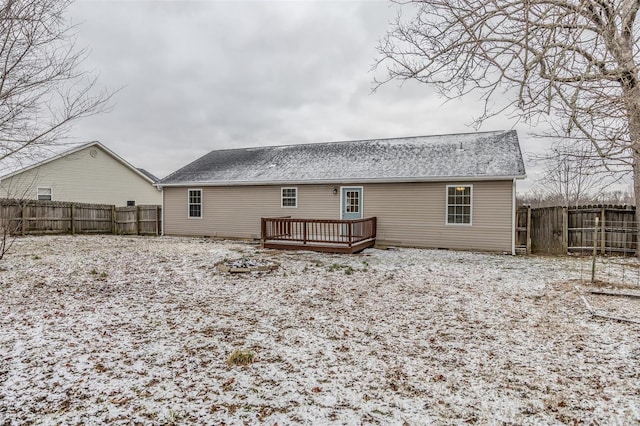 snow covered rear of property with a deck, a shingled roof, and a fenced backyard