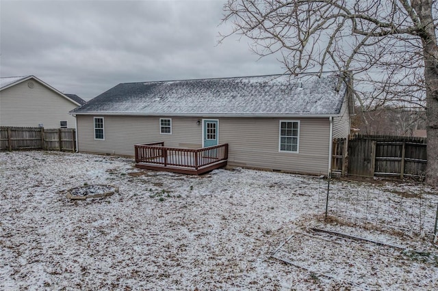 snow covered property featuring a shingled roof, a fenced backyard, and a wooden deck