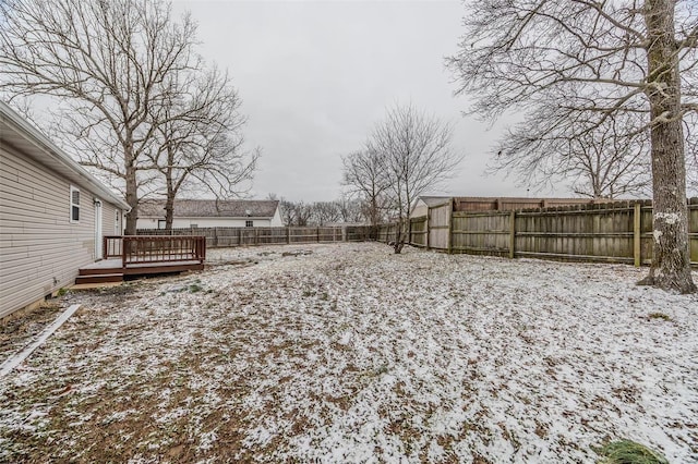 snowy yard featuring a fenced backyard and a wooden deck