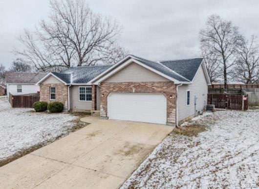 single story home with brick siding, fence, driveway, and an attached garage