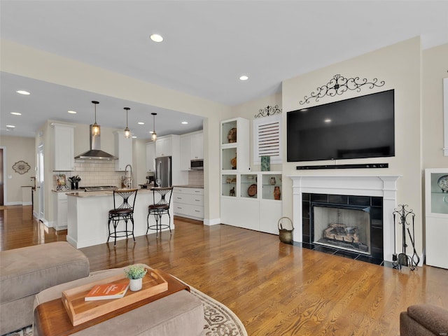 living room with a tiled fireplace, wood finished floors, and recessed lighting