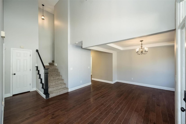 interior space with baseboards, dark wood finished floors, stairs, a towering ceiling, and a chandelier