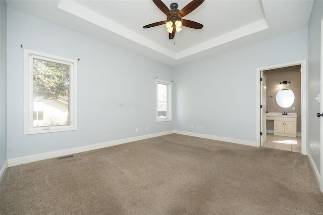 empty room featuring visible vents, ceiling fan, baseboards, light carpet, and a raised ceiling