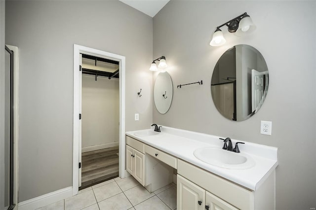 full bathroom with tile patterned floors, double vanity, a walk in closet, and a sink