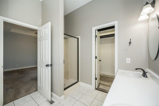 bathroom with tile patterned flooring, a stall shower, double vanity, and a sink