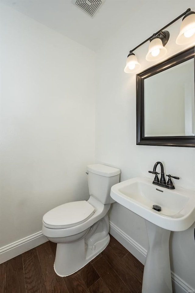 half bathroom featuring visible vents, toilet, baseboards, and wood finished floors