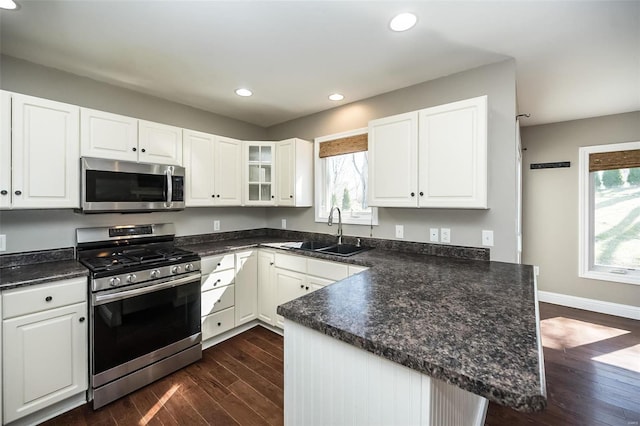 kitchen featuring a sink, dark countertops, a peninsula, and stainless steel appliances