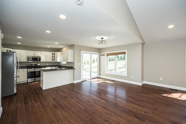 kitchen featuring open floor plan, stainless steel appliances, glass insert cabinets, and baseboards