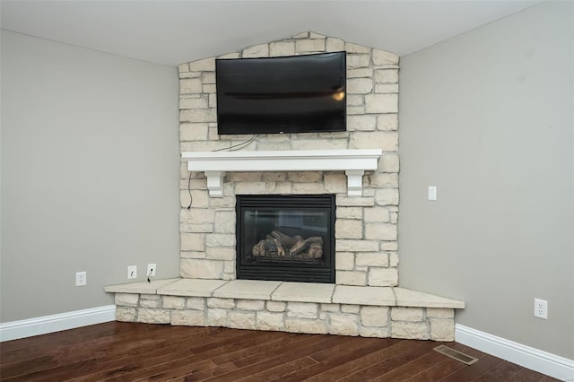 details featuring visible vents, a fireplace, baseboards, and wood finished floors