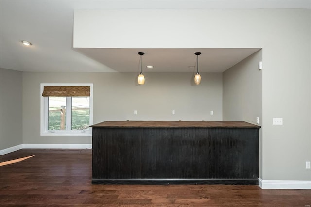 kitchen featuring wood counters, baseboards, dark wood-type flooring, and hanging light fixtures