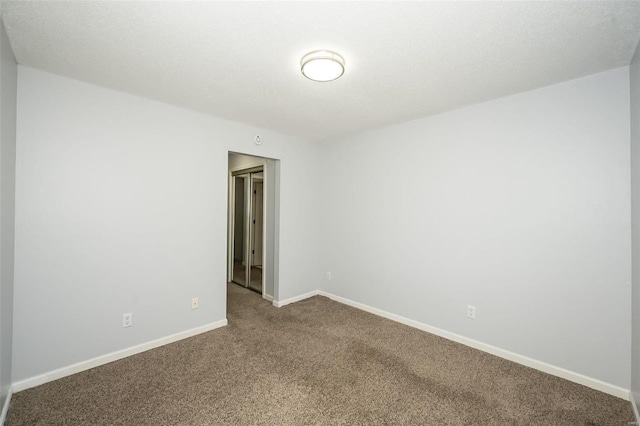 unfurnished room featuring baseboards and dark carpet