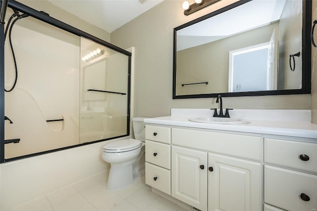 bathroom featuring tile patterned floors, toilet, vanity, and bath / shower combo with glass door