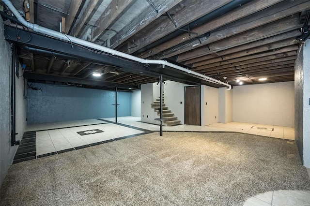 finished basement with stairs, carpet flooring, and tile patterned flooring