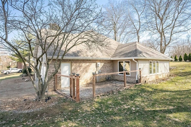 view of side of home featuring a lawn, brick siding, and roof with shingles