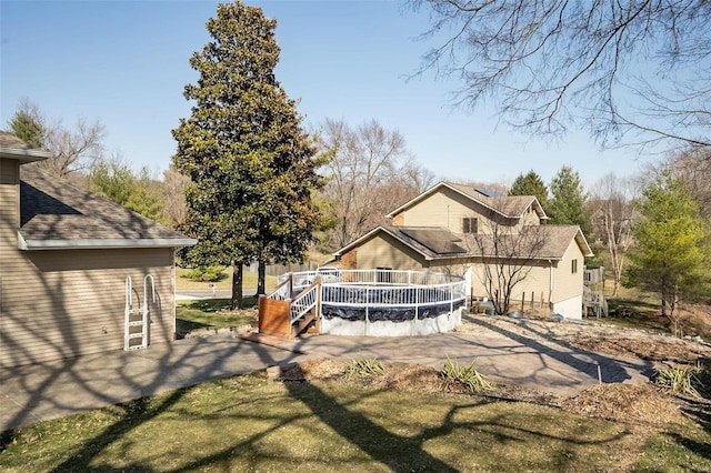 back of house featuring a shingled roof and a wooden deck