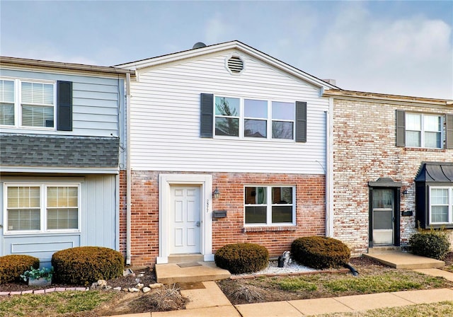 townhome / multi-family property featuring brick siding and roof with shingles