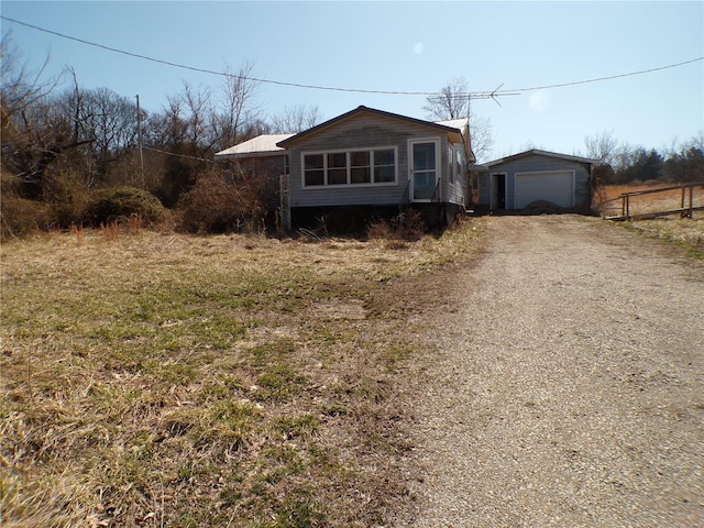 view of front of property with a garage, an outbuilding, and dirt driveway