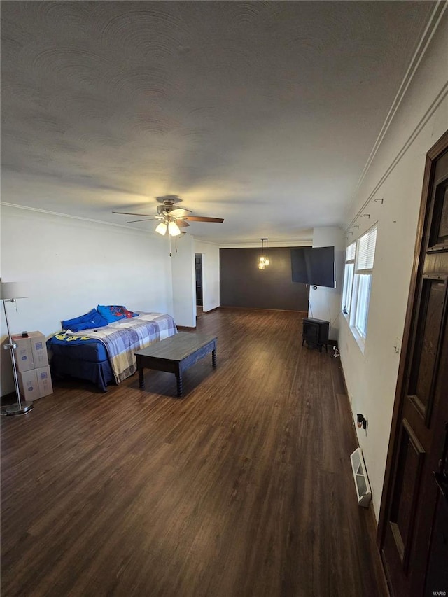 bedroom featuring visible vents, ornamental molding, a ceiling fan, a textured ceiling, and dark wood-style flooring