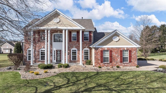 neoclassical / greek revival house featuring brick siding and a front lawn