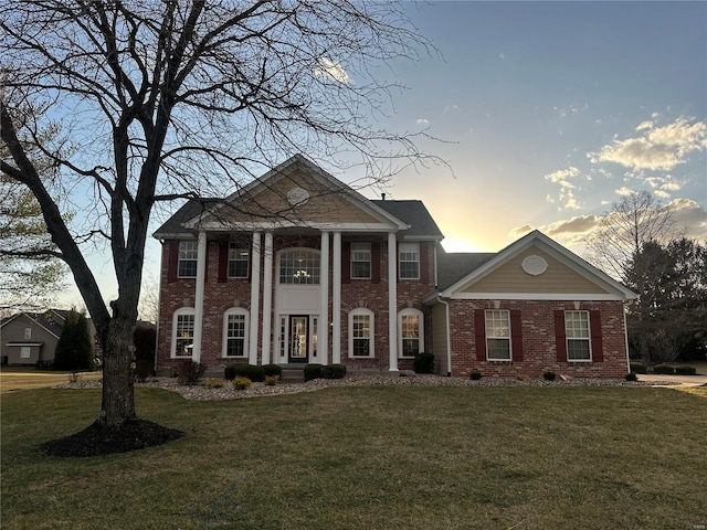 greek revival inspired property with brick siding and a front lawn