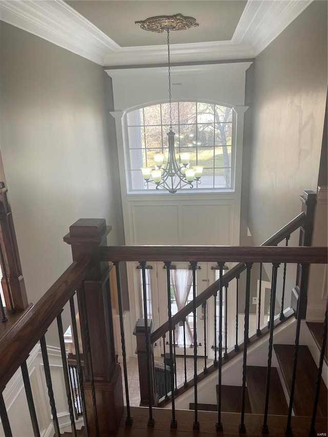 stairs with an inviting chandelier and crown molding