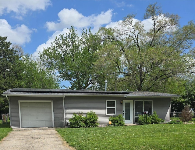 ranch-style house with an attached garage, roof mounted solar panels, driveway, and a front yard