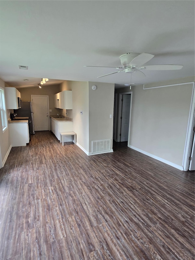 unfurnished living room featuring baseboards, visible vents, and dark wood-type flooring