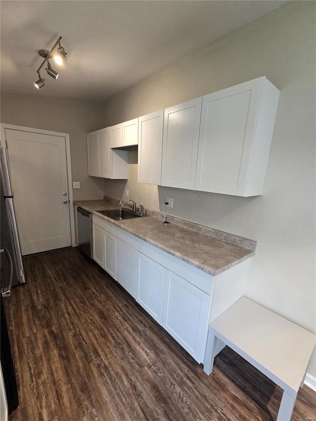 kitchen with stainless steel dishwasher, dark wood-type flooring, light countertops, white cabinetry, and a sink