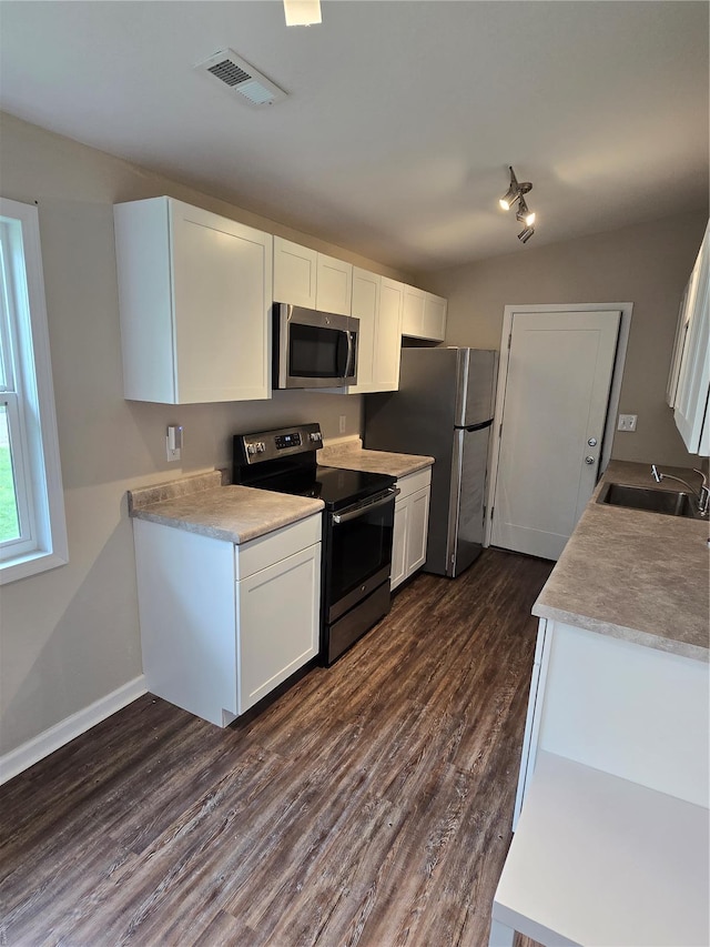 kitchen with visible vents, dark wood-style flooring, white cabinetry, a sink, and appliances with stainless steel finishes