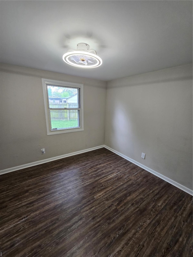 unfurnished room with baseboards and dark wood finished floors
