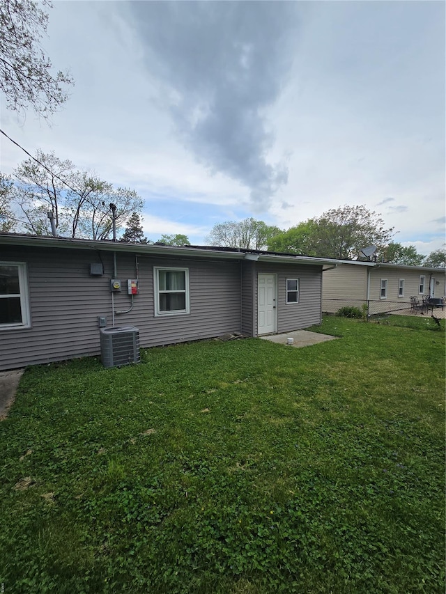 rear view of house with a yard and cooling unit