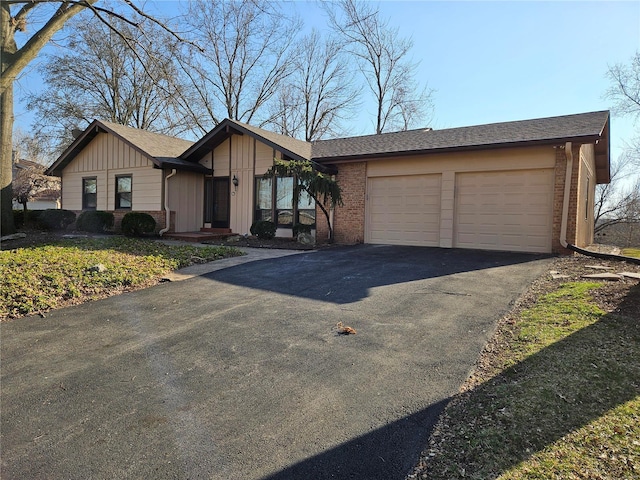 view of front of home with brick siding, driveway, a garage, and board and batten siding