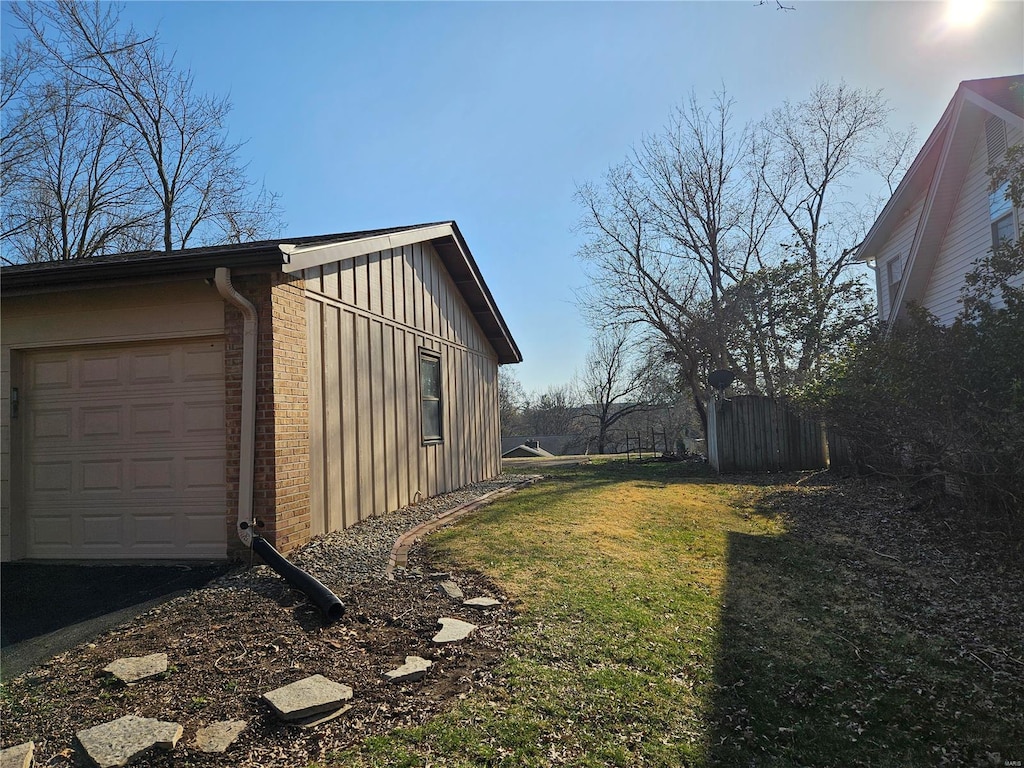 view of property exterior with brick siding, a garage, board and batten siding, and a yard