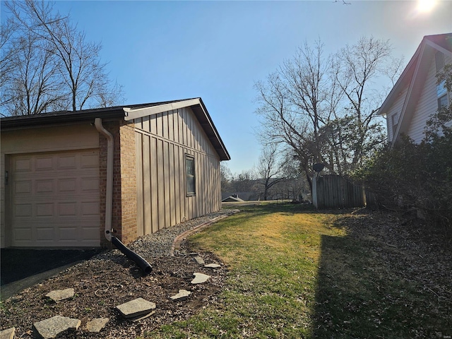 view of property exterior with brick siding, a garage, board and batten siding, and a yard