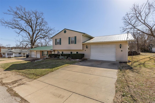 split level home with a garage, metal roof, driveway, and a front lawn