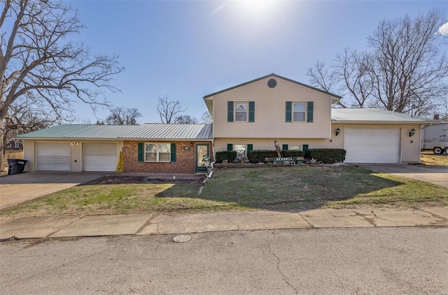 tri-level home with brick siding, concrete driveway, metal roof, a garage, and a front lawn