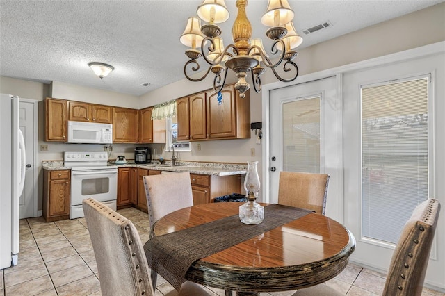 dining room featuring a chandelier, light tile patterned floors, a textured ceiling, and visible vents