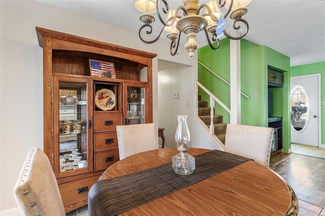 dining space featuring stairway, a chandelier, a textured ceiling, and wood finished floors