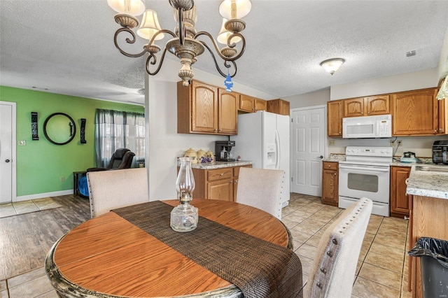 kitchen with light tile patterned floors, light countertops, an inviting chandelier, a textured ceiling, and white appliances